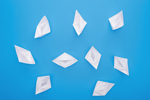 Top view of white paper boats on blue surface