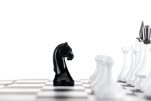 selective focus of chessboard with white chess figures and black knight isolated on white