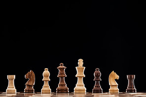 wooden chessboard with brown and beige chess pieces isolated on black
