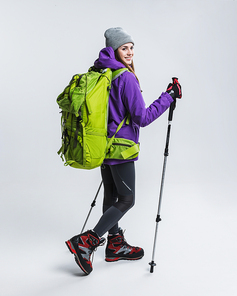 young hiker in sportswear with backpack and hiking sticks, isolated on grey