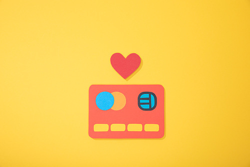 top view of red paper icon of credit card with paper heart isolated on yellow