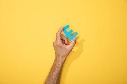 cropped view of man holding blue paper pound on yellow