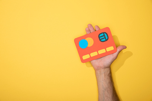 cropped view of man holding red paper credit card on yellow