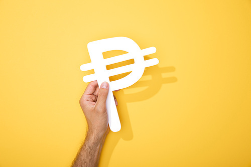 cropped view of man holding paper peso currency signs on yellow