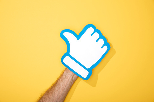 cropped view of man with white paper thumb up on yellow