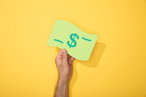 cropped view of man holding paper icon of dollar banknote on yellow