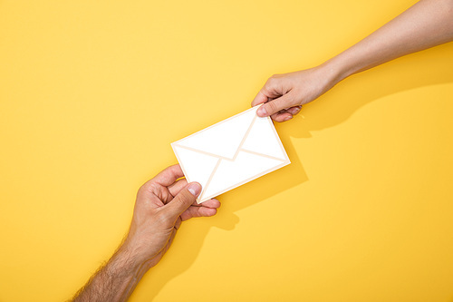 cropped view of man and woman holding paper icon of white envelope on yellow