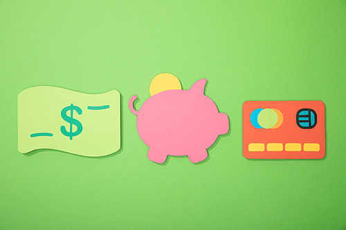 flat lay with piggy bank, credit card and dollar banknote isolated on green