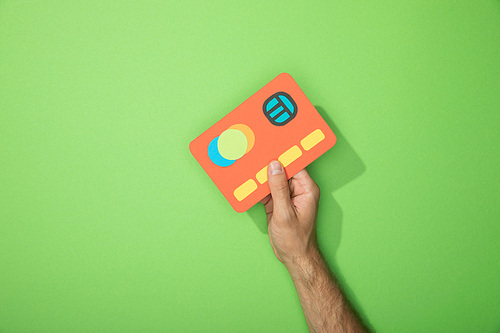cropped view of man holding red paper icon of credit card on green