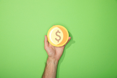 cropped view of man holding paper yellow coin on green