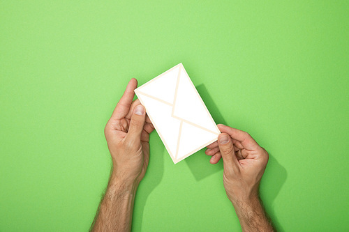 cropped view of man holding paper icon of envelope on green