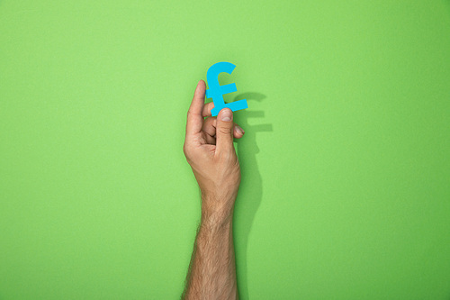 cropped view of man holding paper icon of pound currency sign on green