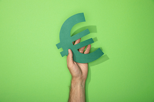 cropped view of man holding euro currency sign on green