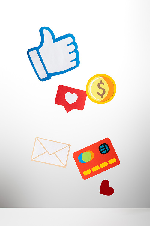 colorful paper cut with envelope, coin, credit card, hearts and thumb up on white background