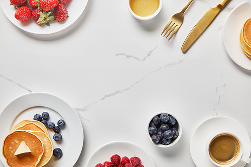 top view of tasty breakfast with pancakes, honey, different kinds of berries and cup of coffee