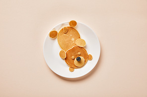 top view of pancakes on plate with one blueberry on pink, bear concept