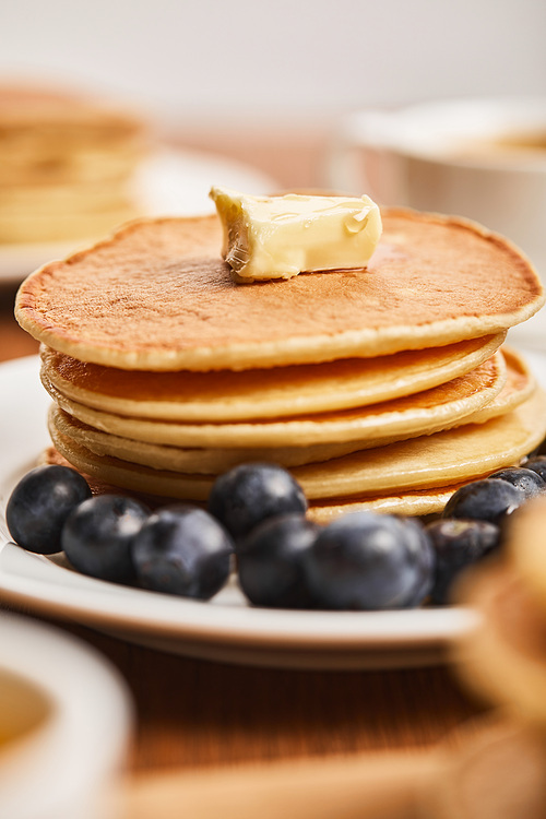 selective focus of pancakes with butter and blueberries on white plate