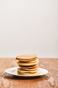 tasty pancakes for breakfast on white plate on wooden surface isolated on grey
