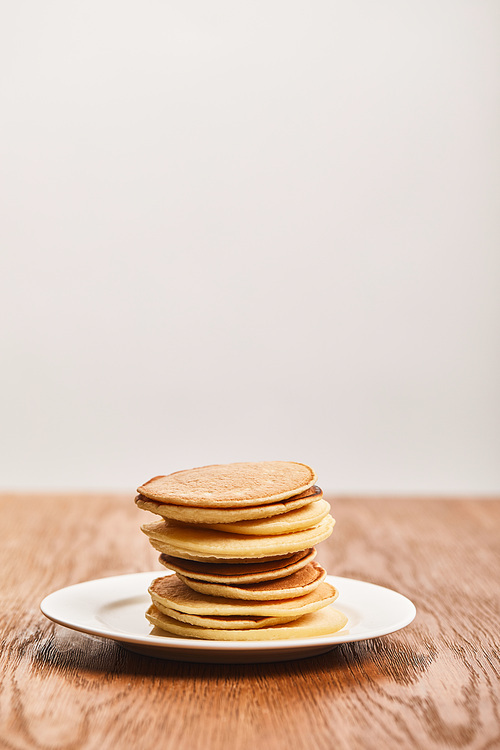 tasty pancakes for breakfast on white plate on wooden surface isolated on grey