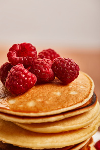 close up view of pancakes with raspberries on wooden surface