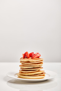 pancakes for breakfast with strawberries on white plate isolated on grey