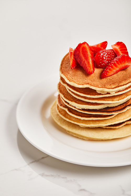 tasty pancakes with strawberries on white plate on textured surface
