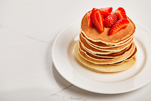 tasty pancakes for breakfast with strawberries on white plate on textured surface
