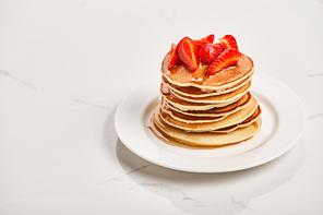 plate with pancakes, strawberries and syrup on textured surface