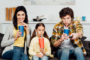 man and adorable daughter drinking soda near happy wife at home