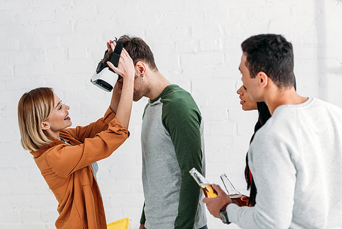 multiethnic friends putting on virtual reality headset