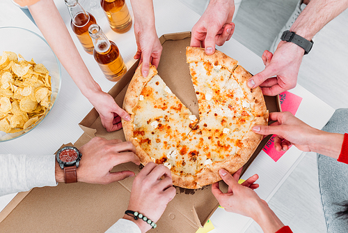 cropped view of men and women stretching hands to pizza
