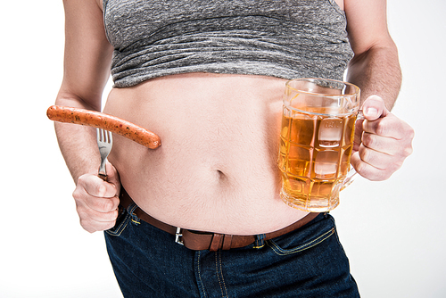 cropped view of overweight man showing belly and holding glass of beer with grilled sausage isolated on white