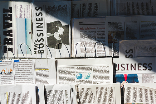 different  business and travel newspapers on stand in sunshine