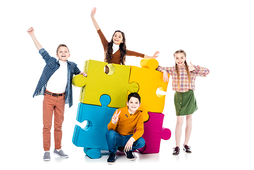 cheerful kids posing near colorful jigsaw puzzle pieces on white