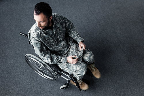 overhead view of disabled man in military uniform sitting in wheelchair and looking away