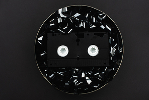 top view of VHS cassette on black film strip in tin case isolated on black