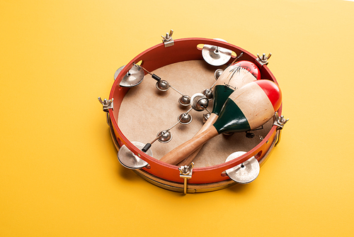 Wooden colorful maracas on tambourine on yellow background