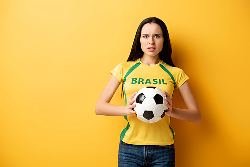stressed female football fan holding ball on yellow