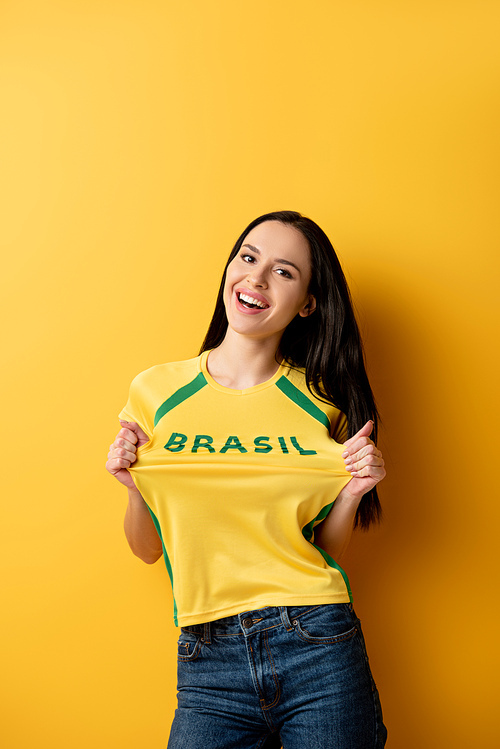 cheerful female football fan in yellow t-shirt with brazil sign on yellow