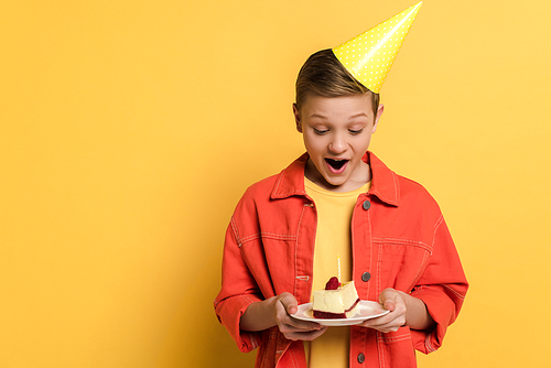 shocked kid holding plate with birthday cake on yellow background