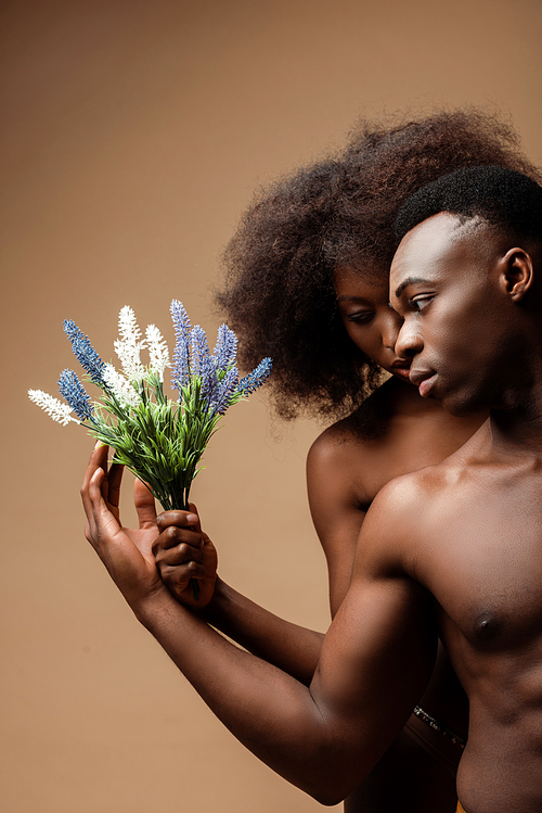 sexy naked african american couple posing with plant on beige
