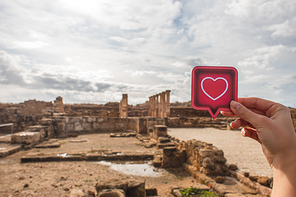 cropped view of woman holding paper heart near ancient House of Theseus