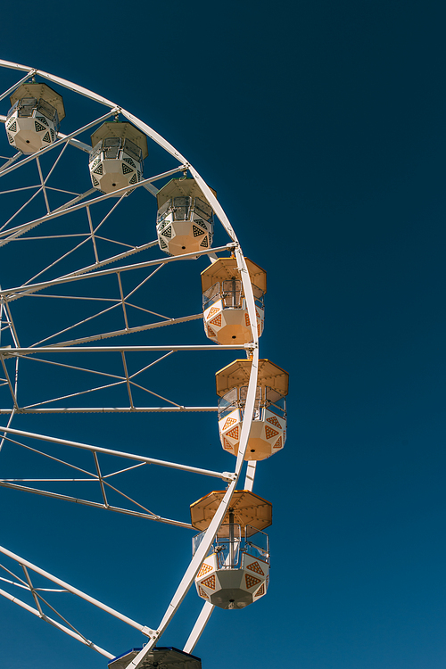 sunshine on metallic ferris wheel against blue sky