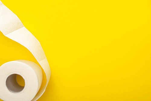 top view of white toilet paper roll on yellow background with copy space