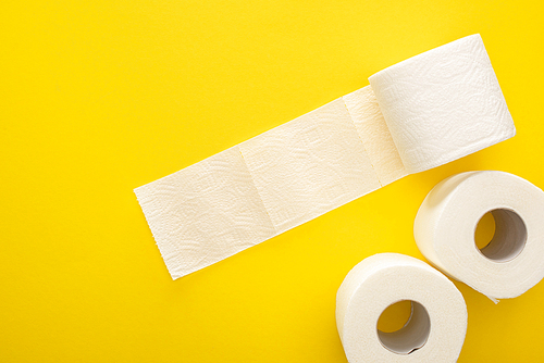 top view of white toilet paper rolls on yellow background