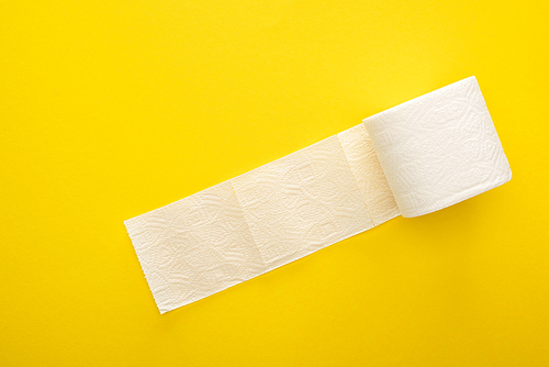 top view of unrolled toilet paper roll on yellow background