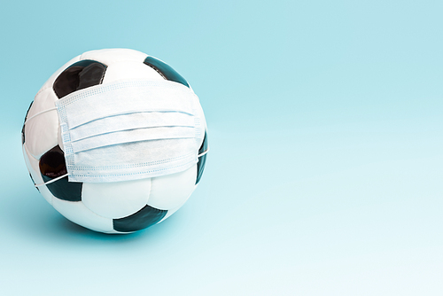 soccer ball in medical mask on blue with copy space