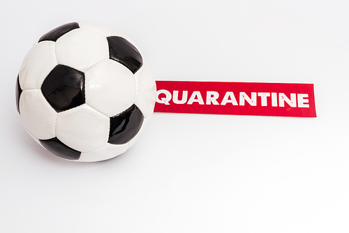 soccer ball near paper with quarantine lettering on white