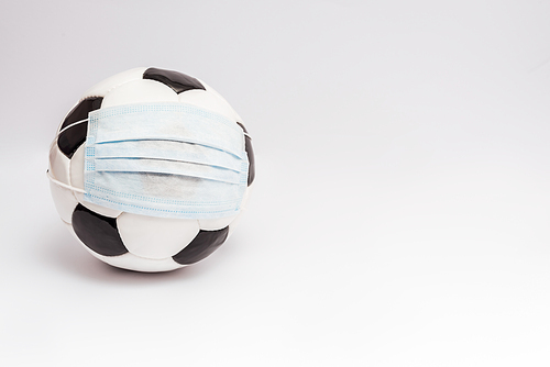 soccer ball in medical mask on white with copy space