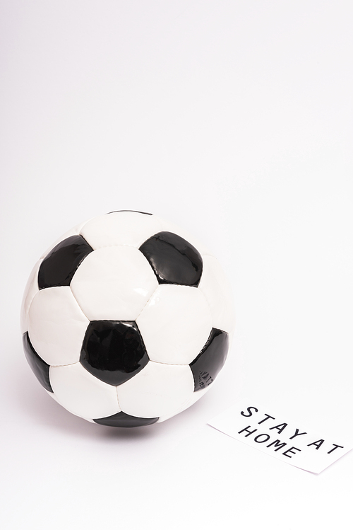 soccer ball near paper with stay at home lettering on white